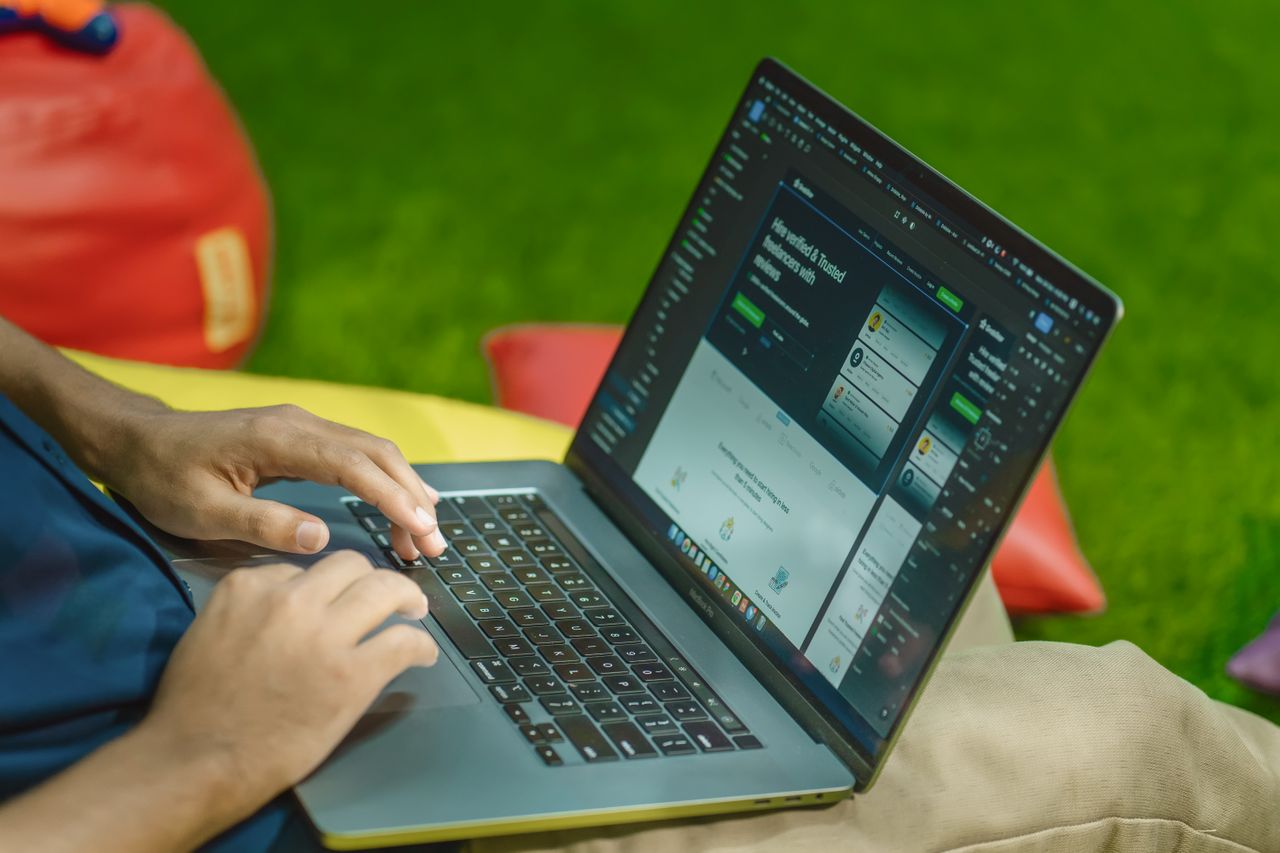 A person using a laptop outdoors on a sunny day, showcasing digital nomad lifestyle.